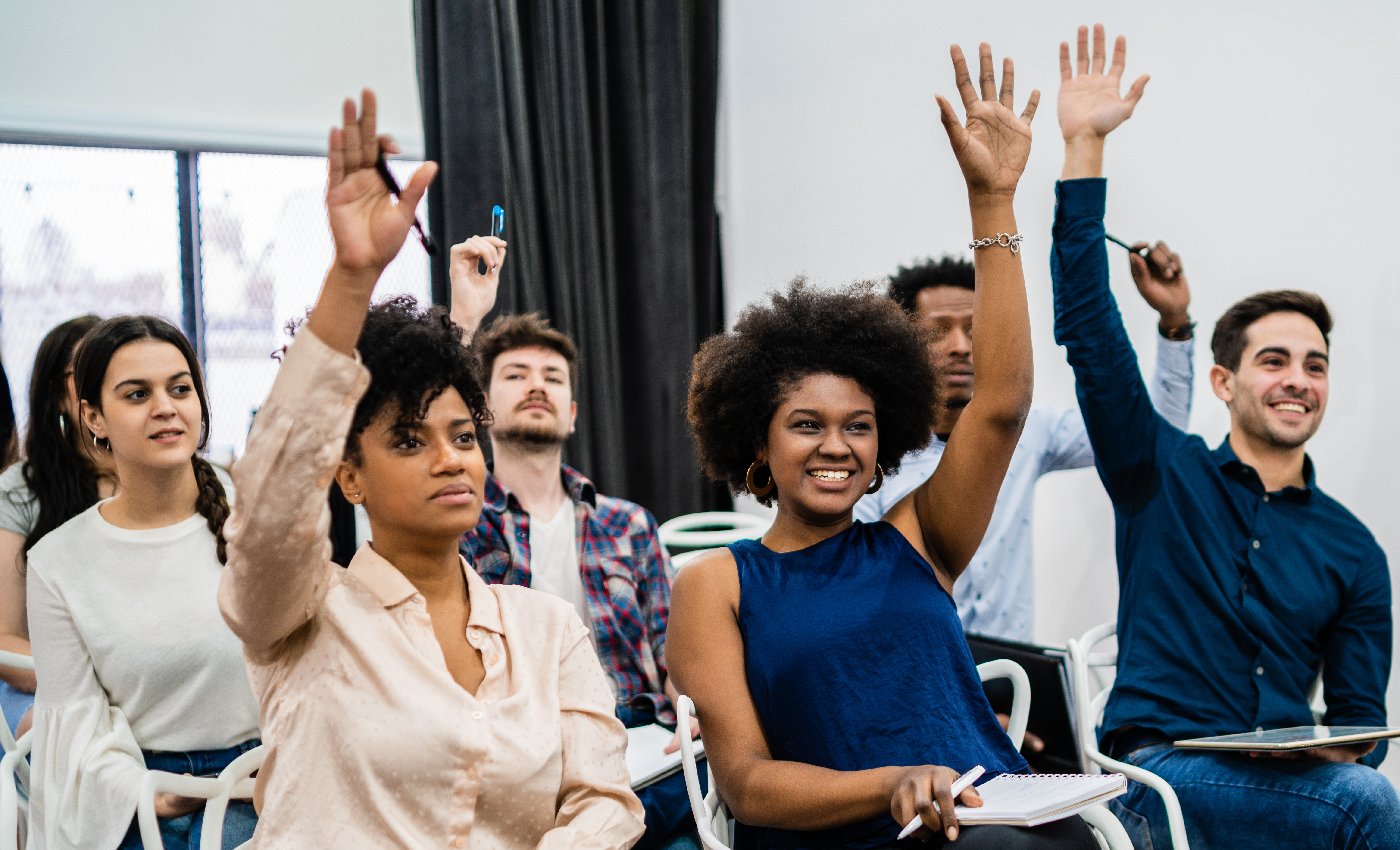 Training participants — engaged classroom session with hands raised